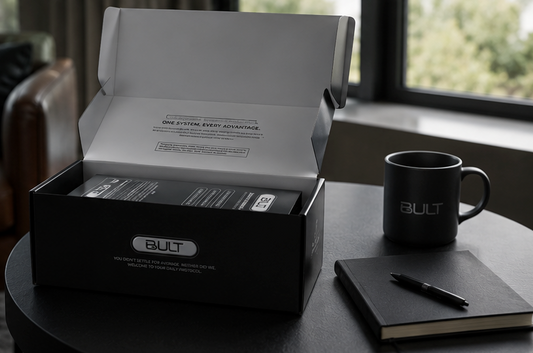 A box of BULT's best multivitamin for men sits on a desk next to a notebook, pen and coffee cup