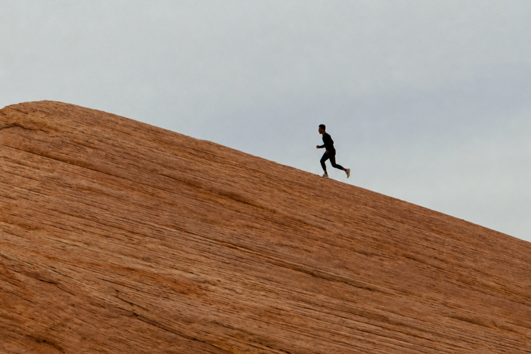 Man running alone up a sandstone slope at sunrise